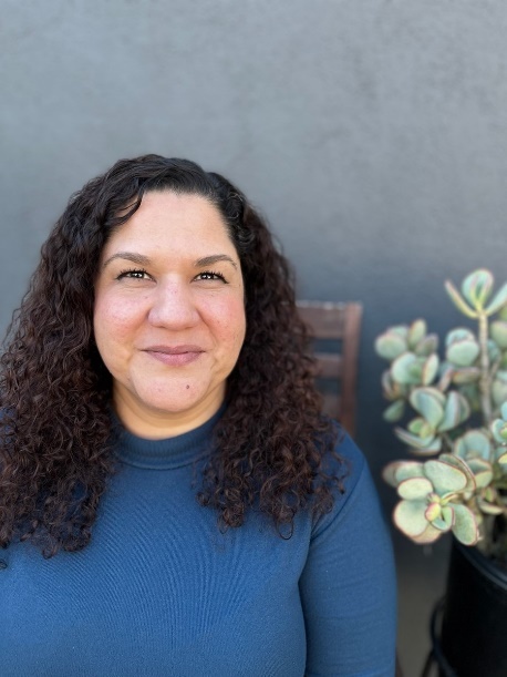 A person with curly hair and blue shirt

Description automatically generated