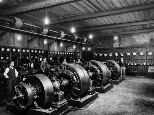 A group of men standing in a room with large machines

AI-generated content may be incorrect.