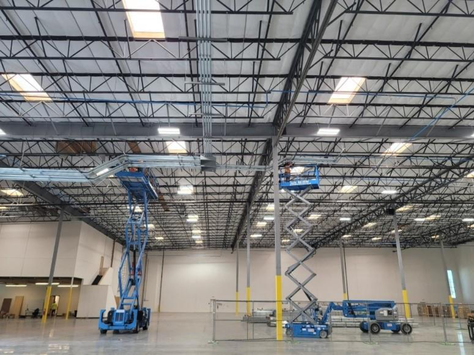 A large warehouse with blue lift machines
AI-generated content may be incorrect.